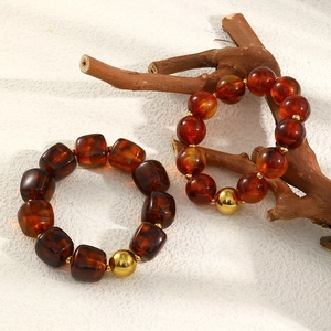 Detail view of amber acrylic beads and a gold accent bead on a wooden branch stand