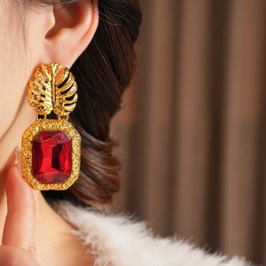 Vue macro des boucles d'oreilles feuille monstera vintage avec grand rubis rectangulaire