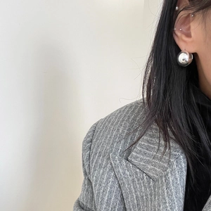 Close-up of a silver spherical stud earring on a model in minimalist fashion style