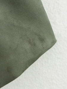 Detailed macro texture of olive green faux suede fabric on a minimalist blazer