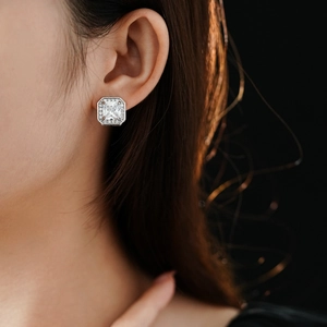 Gros plan d'une boucle d'oreille carrée en argent avec un zircon central et son halo