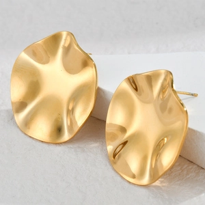 Golden irregular wavy disc earrings in stainless steel on a minimalist white stone background