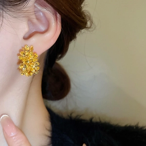 Close-up of a model wearing a gold metallic flower-shaped C-style stud earring