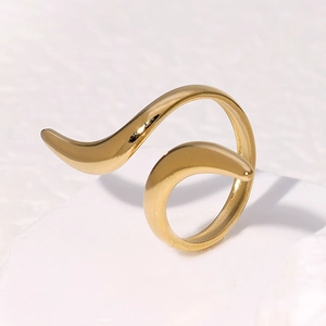 Detailed view of a gold-tone minimalist wave design ring on a white stone background