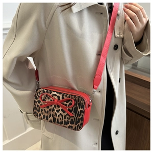 Detail of leopard print crossbody bag with red leather trim and decorative bow
