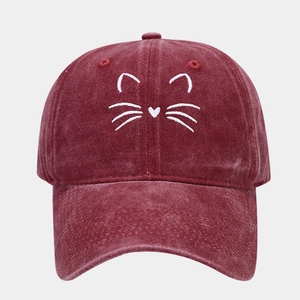 Detailed view of white cat face embroidery on vintage washed burgundy cotton baseball cap