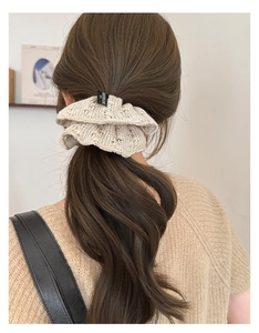 Detail of knitted beige lace scrunchie with Enjoy Love tag on model ponytail