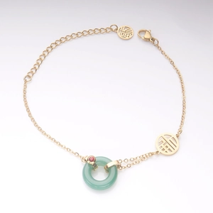 Détail d'un bracelet vintage en or avec pendentif en jade vert et charms de chance
