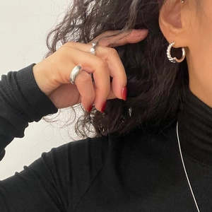 Detail shot of a model wearing woven 925 sterling silver hoop earrings and a thick ring