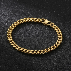Macro shot of gold Cuban link bracelet with metal clasp on black textured background