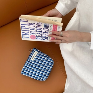 Pochette tissée à carreaux bleu et blanc avec fermeture éclair sur fond en cuir