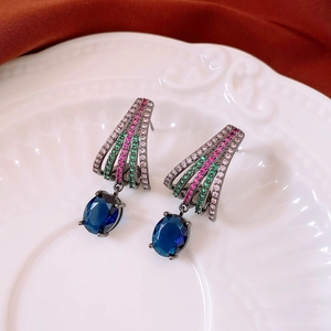 Detail of vintage oval blue gemstone earrings with colorful zircon inlay on white plate