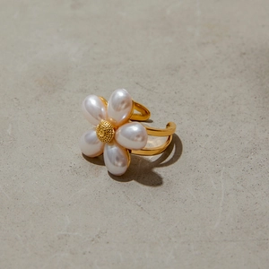 Close-up of elegant gold flower ring with five pearl petals on a neutral matte background