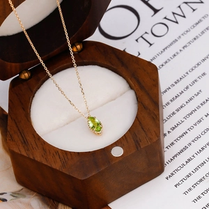 Macro shot of an S925 silver gold-plated necklace with a marquise-cut green gemstone