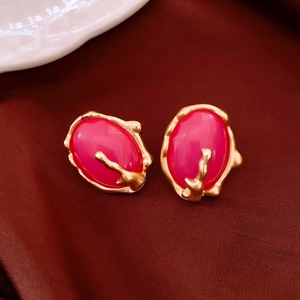 Detail of pink resin earrings with gold pleated texture on luxury velvet fabric