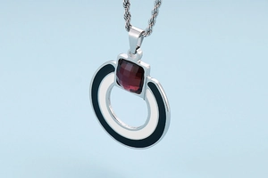 Macro detail of geometric silver necklace with black white enamel and red stone