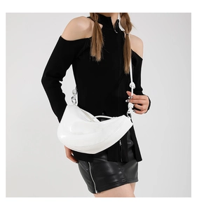 Close-up of white saddle bag with knot strap detail and stitching on black outfit