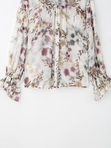 Dettaglio della camicetta floreale in chiffon con righe dorate e polsini a balze