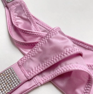 Macro detail of pink satin thong featuring sparkling rhinestone patches and zig-zag stitching
