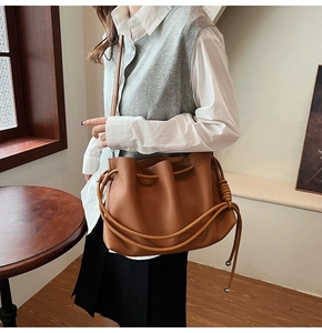 Close-up of brown litchi pattern leather bucket bag with elegant drawstring and knot detail
