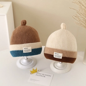 Detail showing knit texture and English label on striped winter beanie for kids