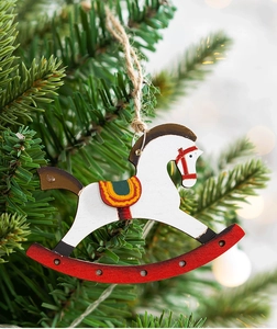 Close-up of white wooden rocking horse ornament with red base on a festive Christmas tree