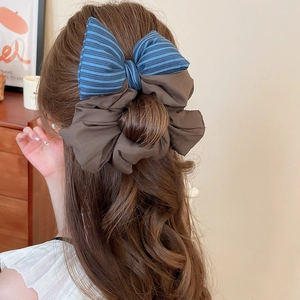 Detail of blue striped and brown fabric bow hair scrunchie shown on long wavy hair