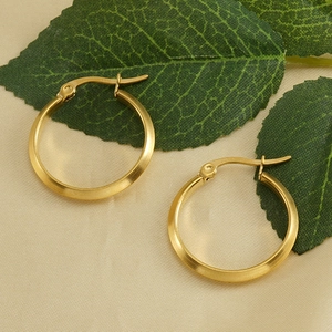 Nahaufnahme der goldenen Edelstahl-Ohrringe mit Scharnierverschluss auf beigem Stoff