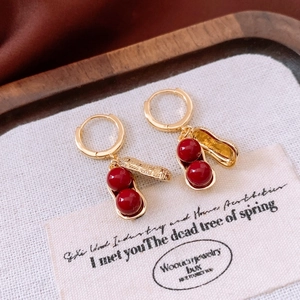 Close-up of golden peanut shaped earrings with red beads on a vintage paper card