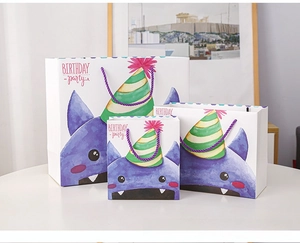 Detailed view of three sizes of cartoon monster gift bags with purple handles