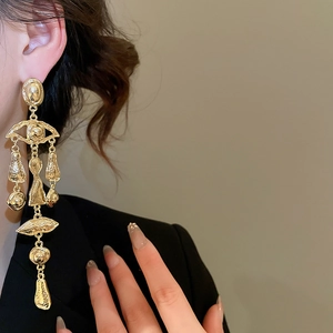Macro detail of vintage gold fringe earrings with lip and eye embossed relief motifs