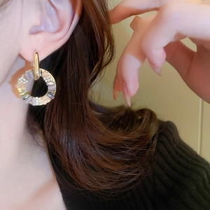 Close-up of model wearing gold geometric hoop earrings with crystals and sparkling rhinestones