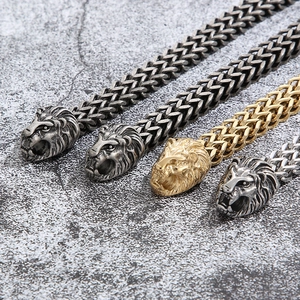 Detail of punk lion head bracelets in silver and gold finishes on a stone background