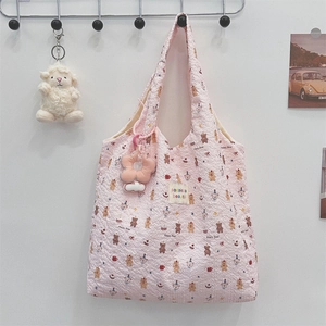 Détail du sac fourre-tout rose matelassé avec motif ours et breloque fleurie au crochet