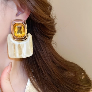 Detail view of retro square resin earrings with gold trim and marble texture on model