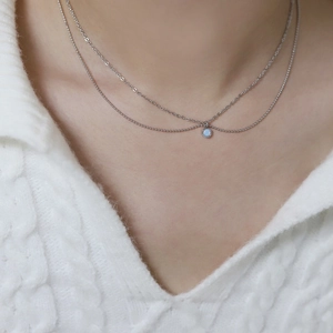Close-up of double-layer silver titanium necklace featuring a round light blue opal stone