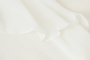 Close-up of white long sleeve shirt showing delicate ruffle trim and fabric texture