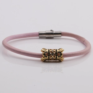 Detail of pink leather bracelet featuring gold hollow bead with cubic zirconia stones