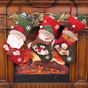Three Christmas stockings with Santa, Snowman and Reindeer hanging on a wooden fireplace