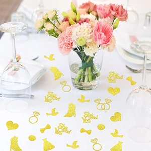 Close-up of golden glitter confetti with diamond rings and She Said Yes text for weddings