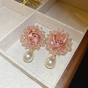 Close-up of pink satin rose earrings with crystal beads and pearl drop pendants