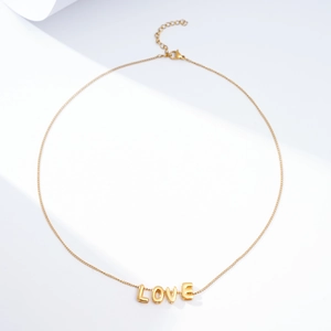 Detailed view of a gold-tone LOVE letter pendant necklace with a lobster clasp closure