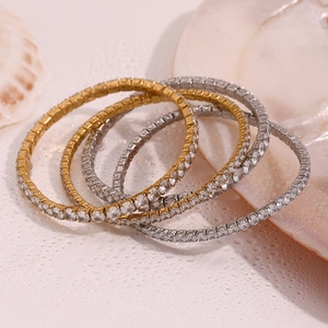 Macro shot of gold and silver tennis bracelets with clear zircons on a white surface