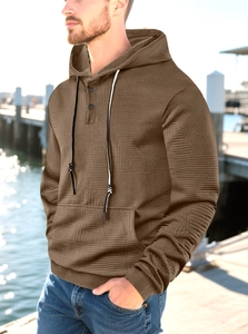 Detail of men's brown hoodie featuring geometric jacquard texture and three-button placket