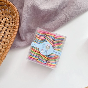 Macro shot of colorful candy-toned elastic hair bands in a transparent square storage box