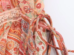 Dettaglio dell'abito con stampa paisley, bordo in pizzo beige e lacci regolabili
