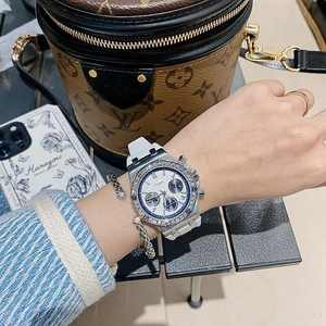 Close-up of silver chronograph watch with diamond bezel and white silicone strap on wrist