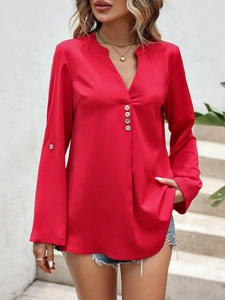 Detalle de blusa roja con cuello en V, botones decorativos y sutil brillo en el tejido