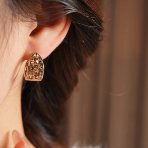Gros plan de boucles d'oreilles dorées en U avec cristaux champagne sur un mannequin