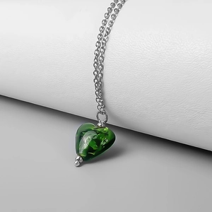 Close-up of heart-shaped green glass pendant with gold foil on silver chain